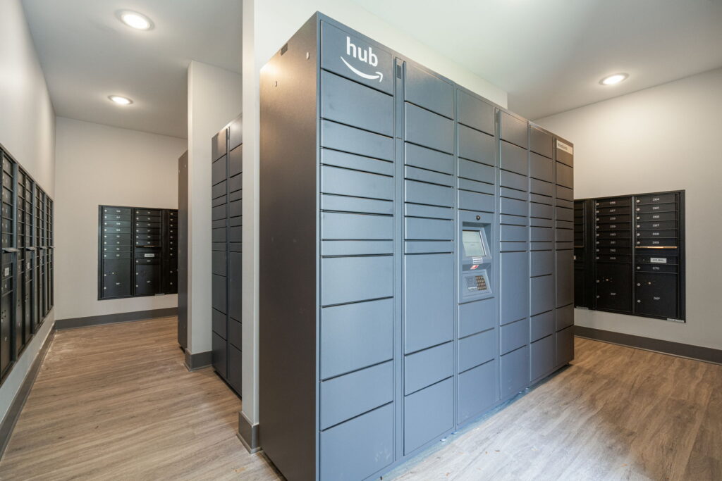 A large mail room with wood flooring and a large, gray Amazon package delivery hub.